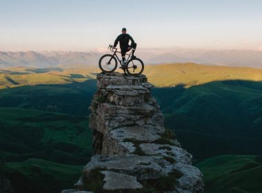 man holding bike while standing on gray mountain