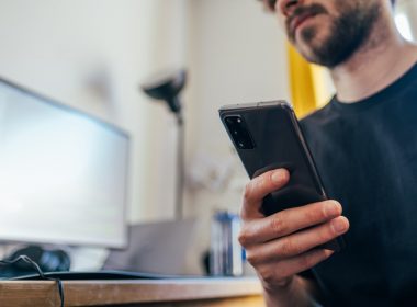 man in black crew neck shirt holding black iphone 5