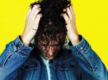 man in blue denim jacket holding his hair