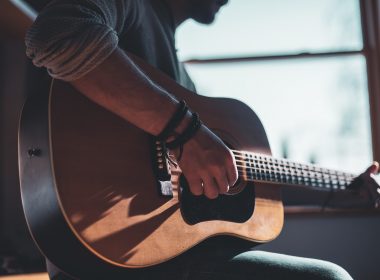man playing acoustic guitar selective focus photography