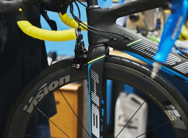 man in black jacket holding black bicycle wheel