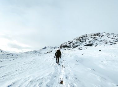 person in black jacket standing on snow covered mountain during daytime