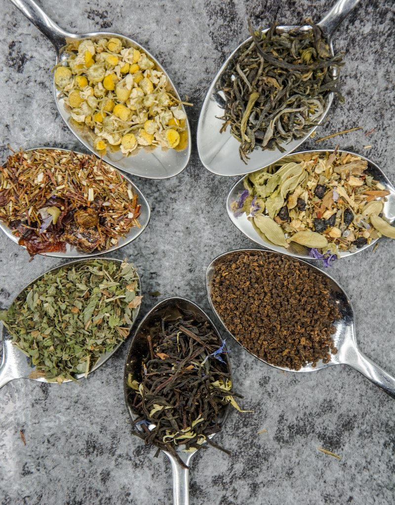 seven different spices and herbs on gray stainless steel spoons