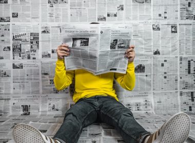 a person sitting on the floor reading a newspaper