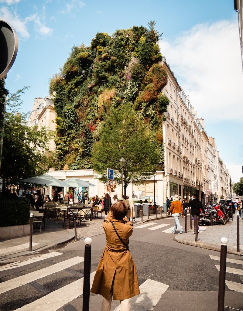 woman in brown jacket standing on sidewalk during daytime