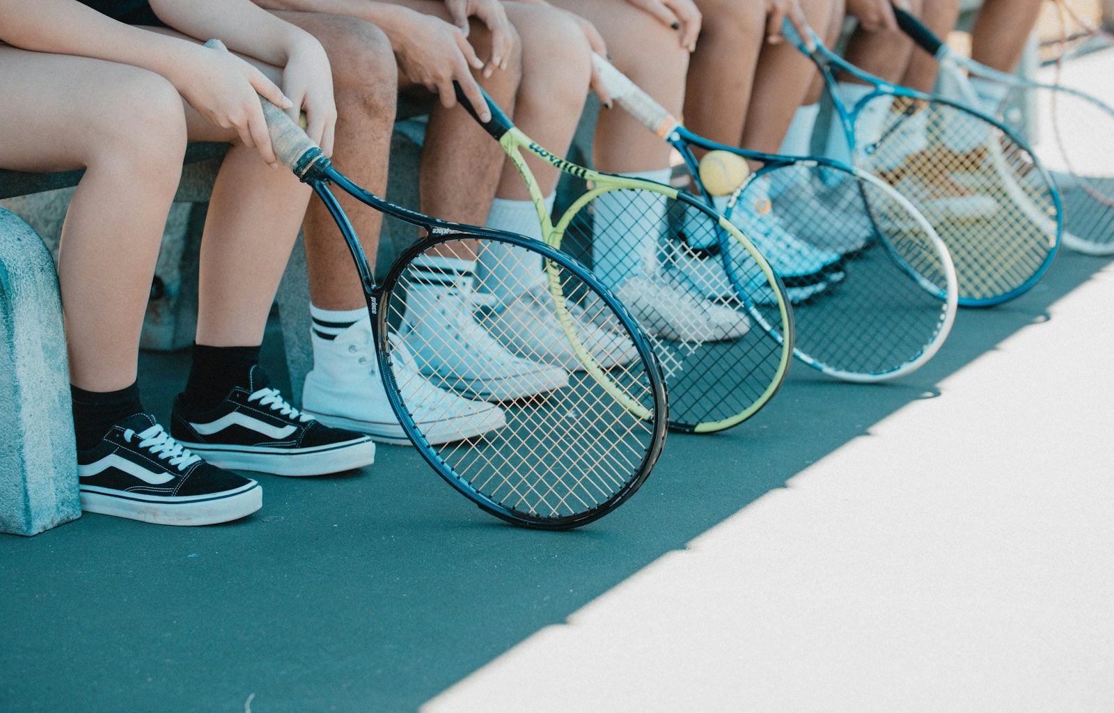 person in black and white nike sneakers holding blue and white tennis racket