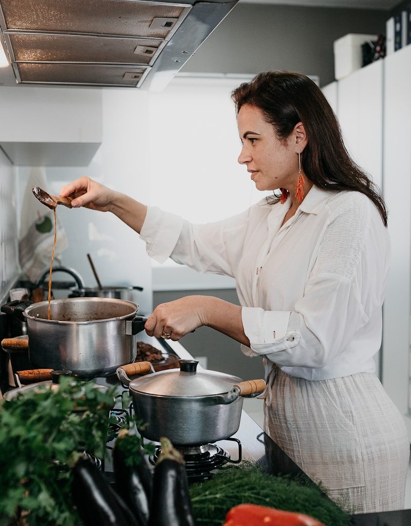 woman in white dress shirt holding stainless steel cooking pot