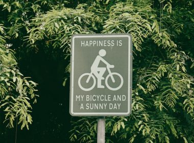 a sign that says happiness is my bicycle and a sunny day
