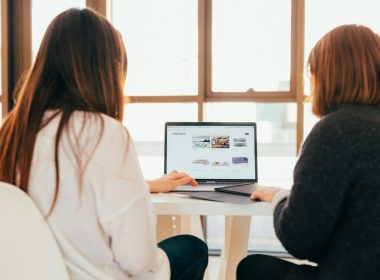 two women talking while looking at laptop computer