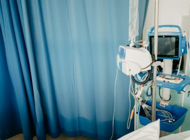 a hospital room with a blue curtain and a monitor