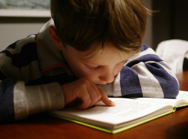 boy in gray and red hoodie reading book