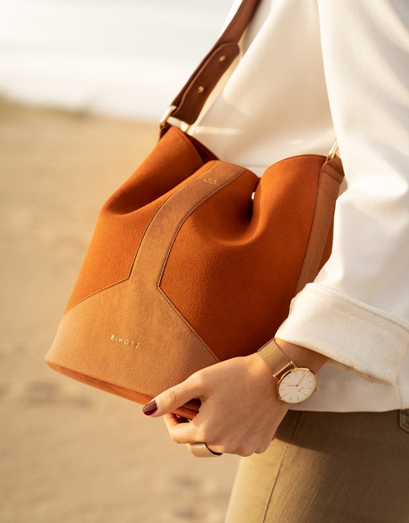 person in white dress shirt holding brown leather handbag