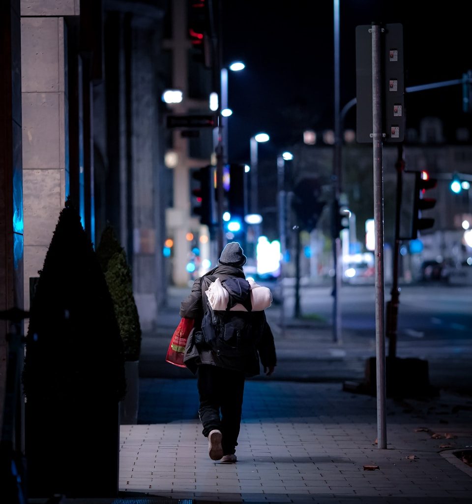 woman in black jacket and black pants walking on sidewalk during night time