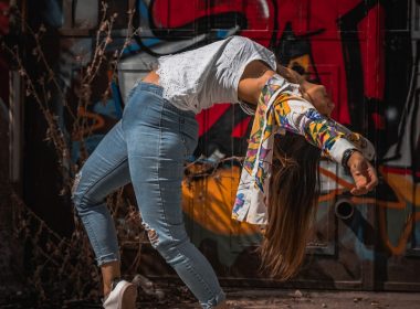 woman in blue denim jeans and white long sleeve shirt standing near red wall