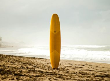 brown surfboard standing on sea shore