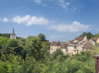 a view of a village with a church steeple in the background