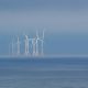 Offshore wind turbines stand in the misty ocean.