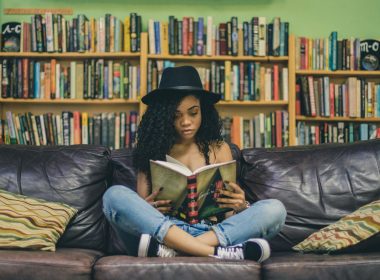 woman reading a book while sitting on black leather 3-seat couch