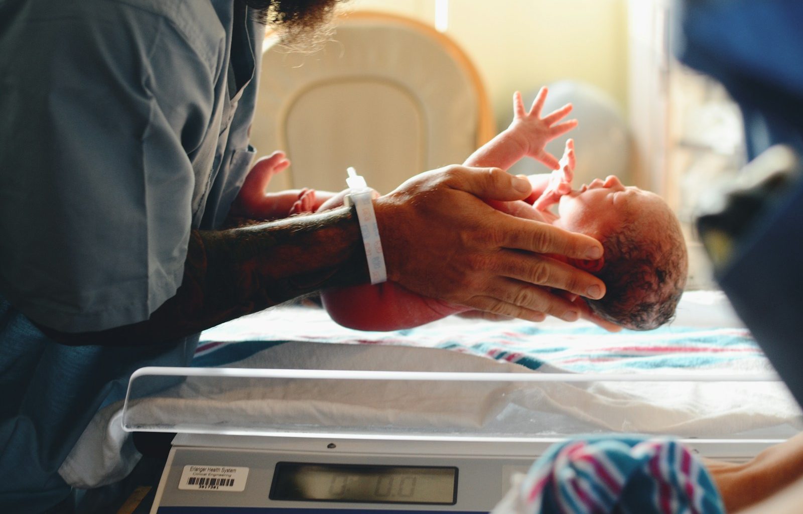 person wearing gray shirt putting baby on scale