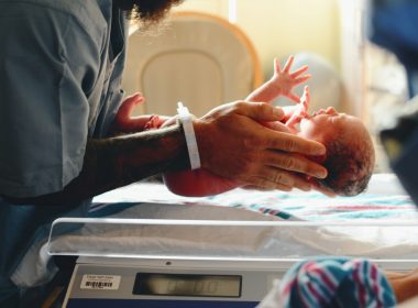 person wearing gray shirt putting baby on scale