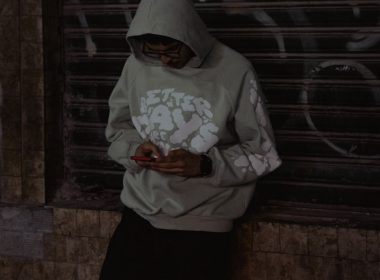 A man in a hoodie looking at his cell phone