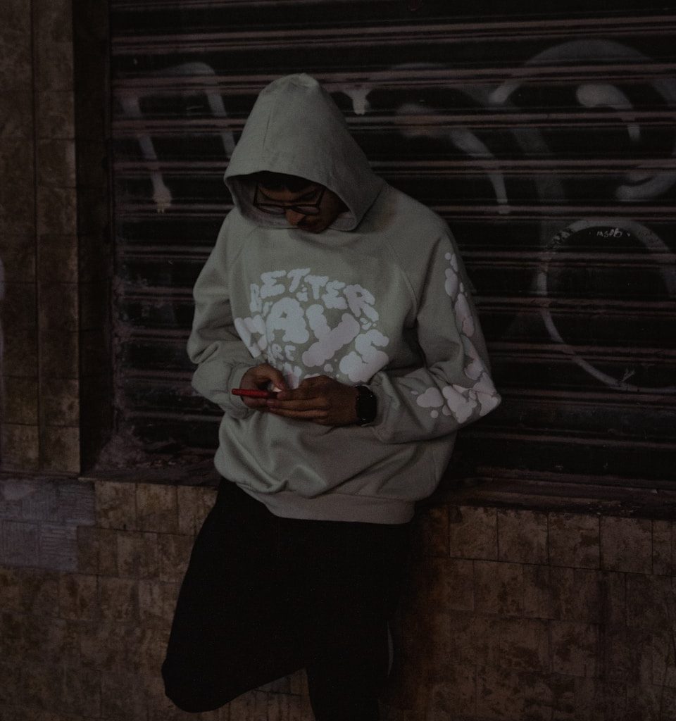 A man in a hoodie looking at his cell phone