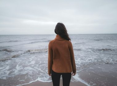 a woman standing on a beach looking out at the ocean