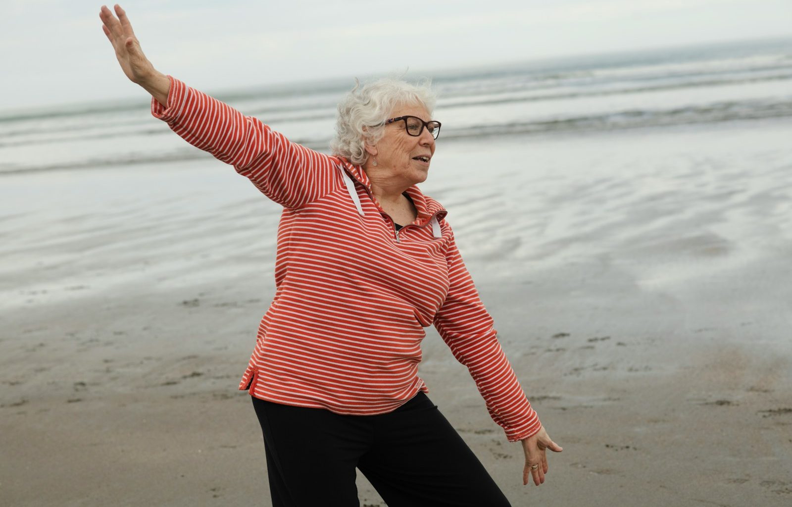 Woman practices tai chi on the beach.