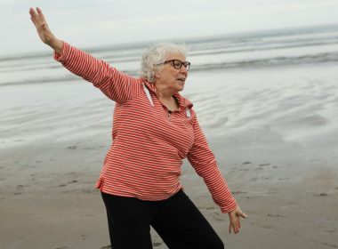 Woman practices tai chi on the beach.
