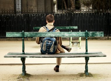 man in brown shirt sitting on bench