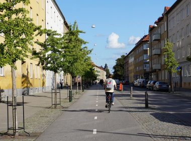 a man riding a bike down a street next to tall buildings