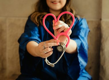 girl in blue jacket holding red and silver ring