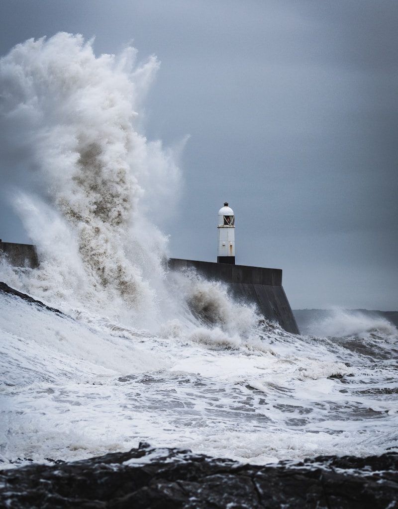 big waves crashing on lighthouse during daytime