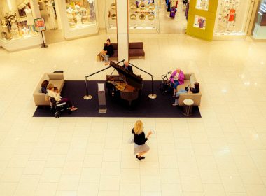 a woman is walking through a mall with a piano