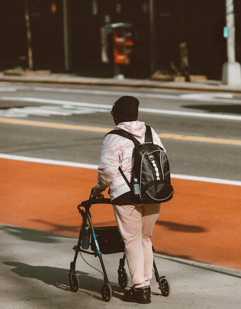 man in black and white jacket and brown pants with black backpack walking on road during