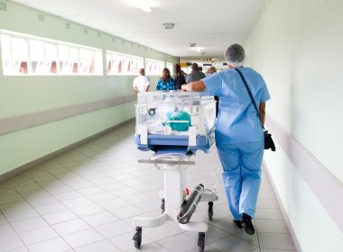 person walking on hallway in blue scrub suit near incubator