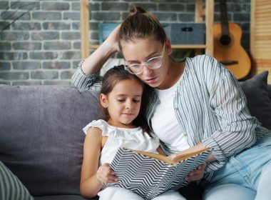 Mother and daughter reading a book together on couch
