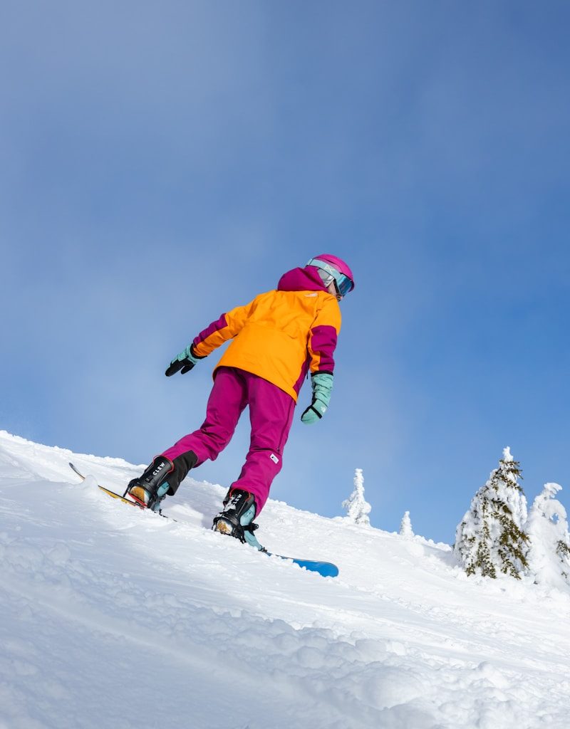 a person riding a snowboard down a snow covered slope