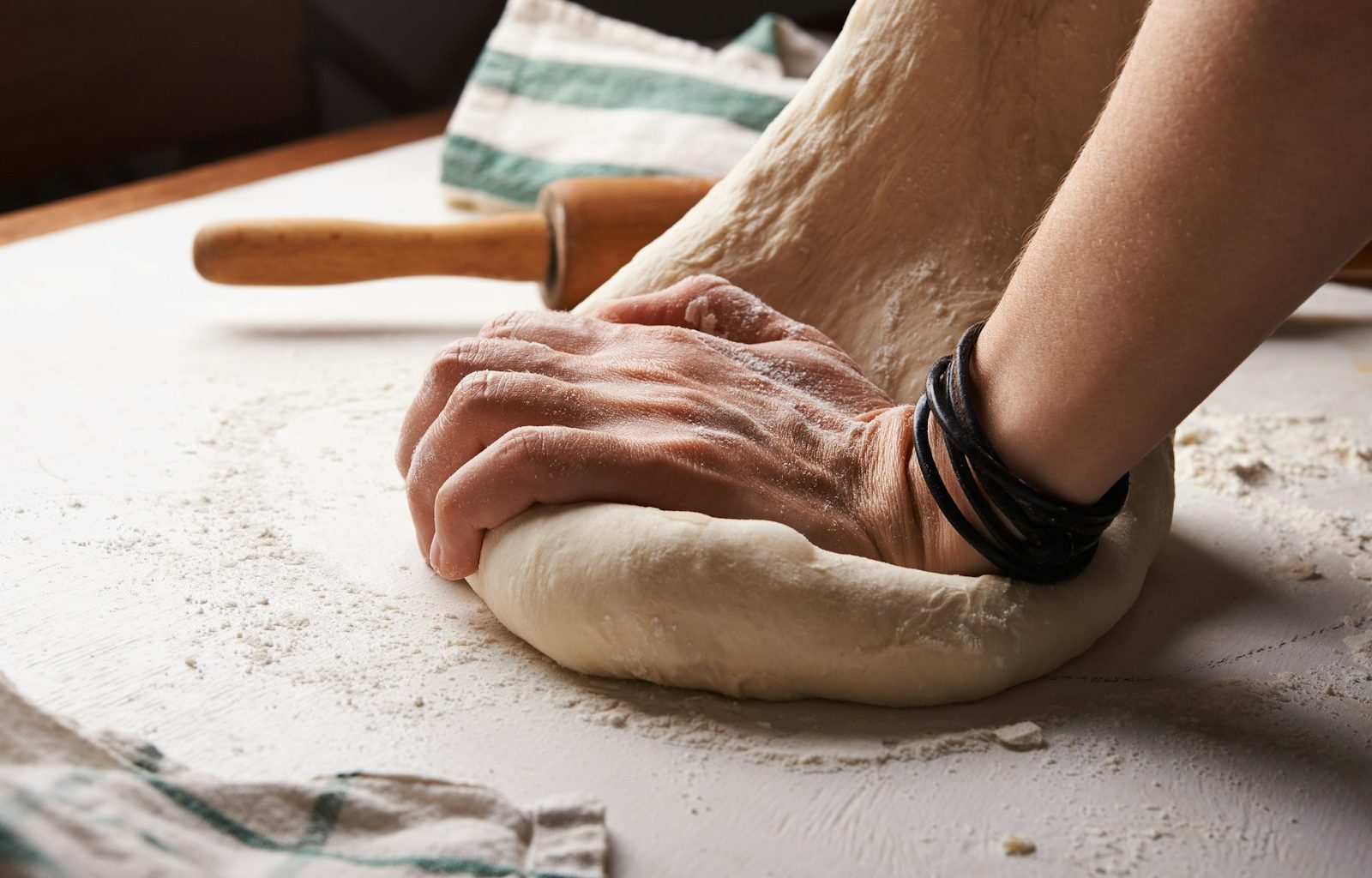 person making dough beside brown wooden rolling pin