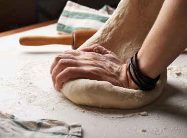 person making dough beside brown wooden rolling pin