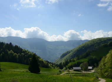 a scenic view of a mountain valley with a house in the foreground