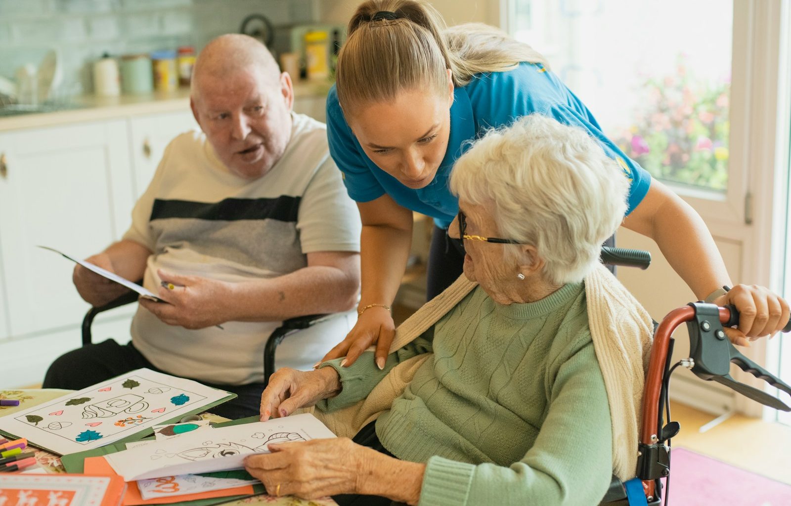 Caregiver assisting elderly couple with coloring
