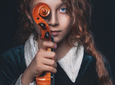 woman in black and white sweater holding brown violin