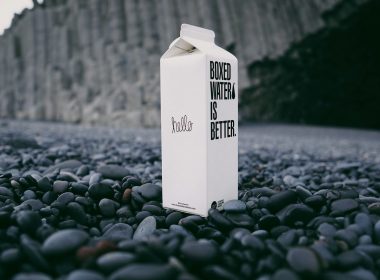 A carton of Boxed Water on a black beach