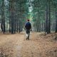 man in black jacket and black pants walking on brown dirt road in forest during daytime