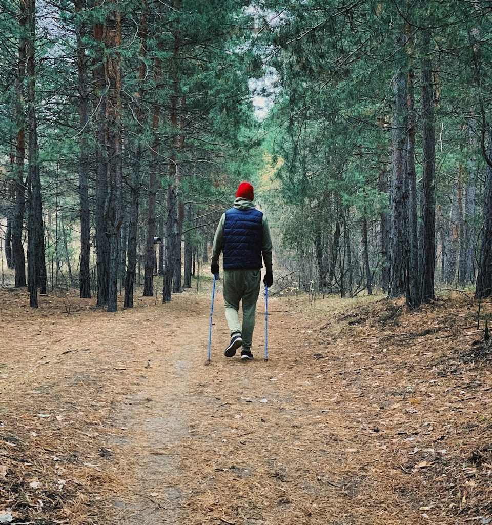 man in black jacket and black pants walking on brown dirt road in forest during daytime