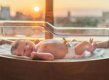baby in white disposable diaper lying on white bathtub