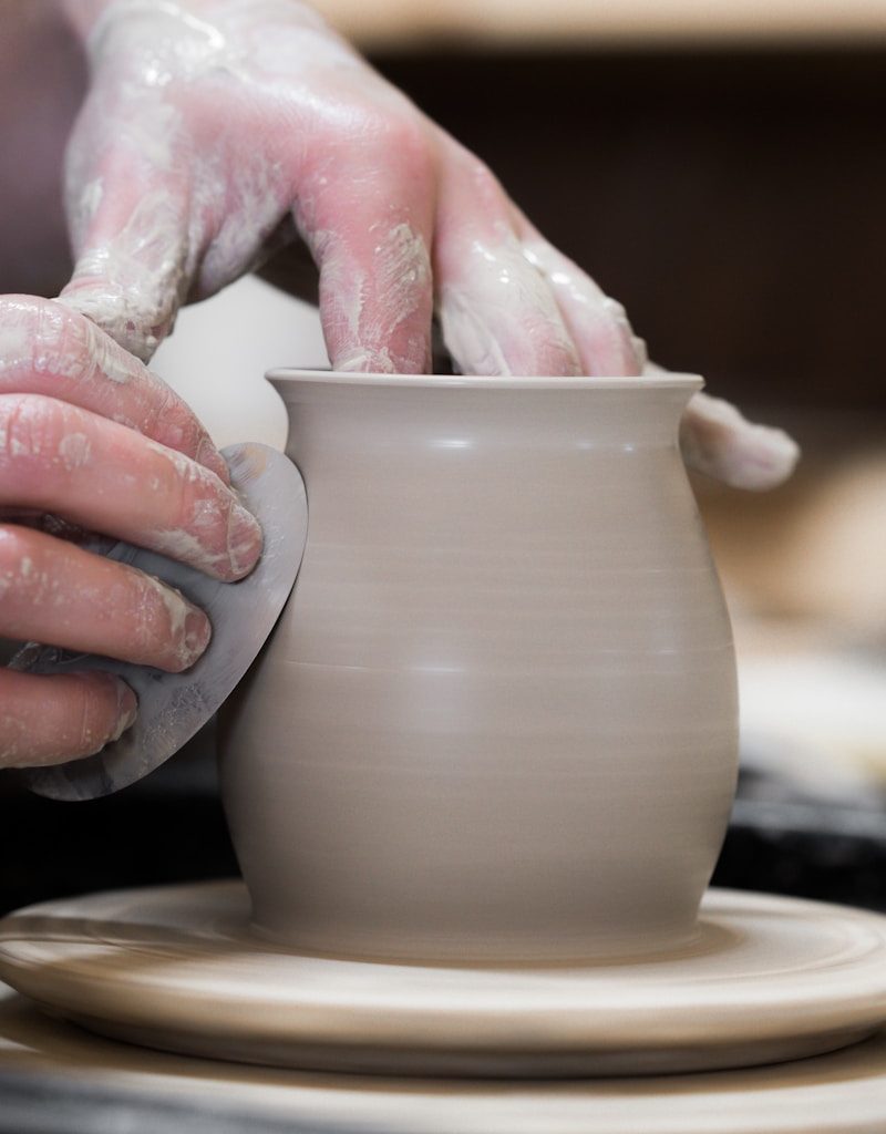 person holding white clay pot