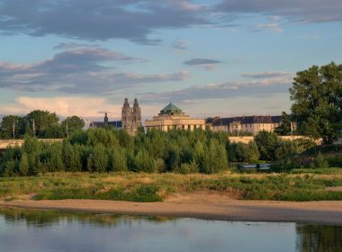 a large building sitting on top of a hill next to a river