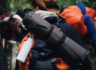 man carrying black sleeping bag and backpack